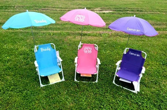 three kid's beach chairs and umbrellas in blue, pink, and purple