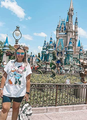 a reviewer at disney world wearing a white t-shirt with minnie mouse and daisy duck on it