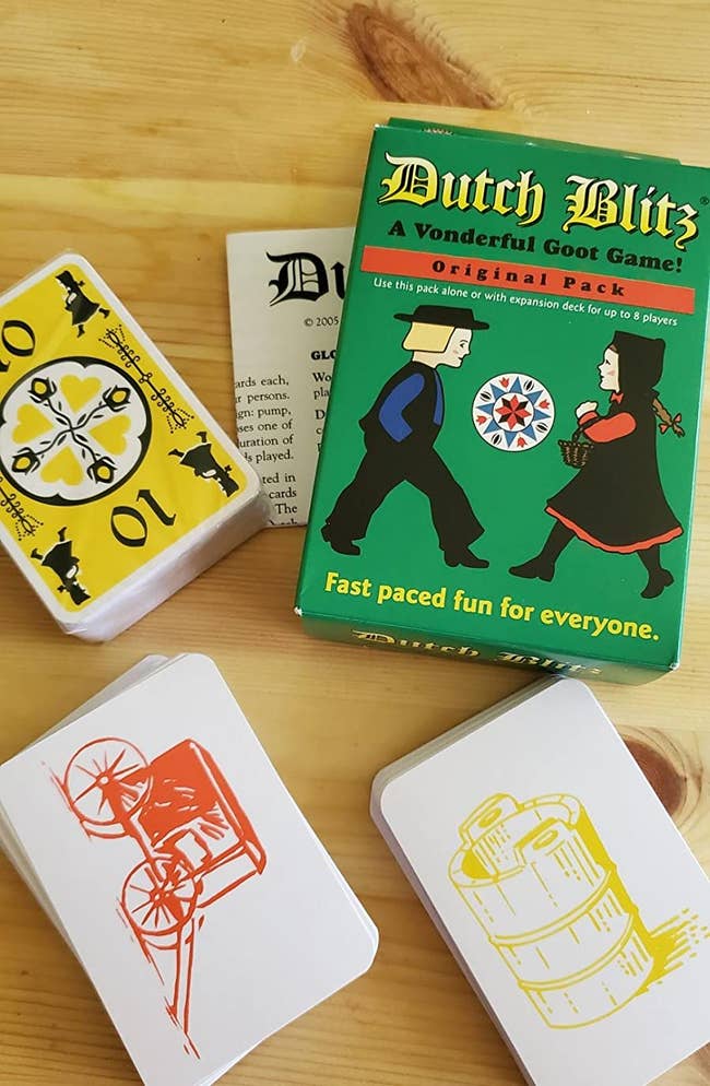 a reviewer photo of the card game box and two stacks of cards, one with a yellow bucket print and one with an orange carriage print 