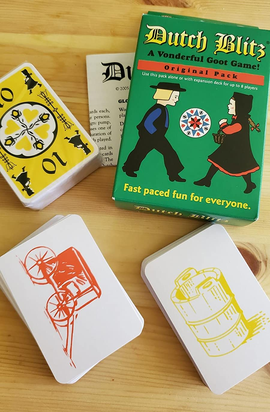 a reviewer photo of the card game box and two stacks of cards, one with a yellow bucket print and one with an orange carriage print 