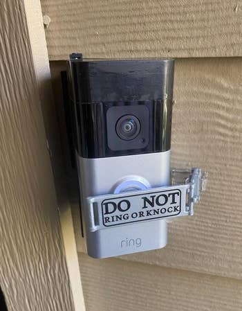Kamera bel pintu dengan tanda bertuliskan,