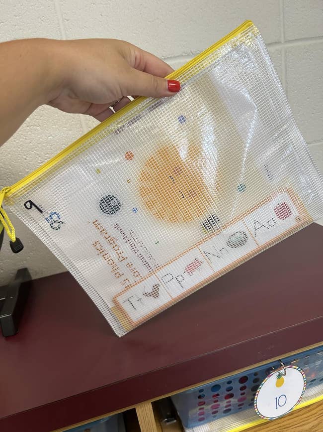 Mesh zipper container held by a hand, containing acquisition flashcards for learning alphabets and planets