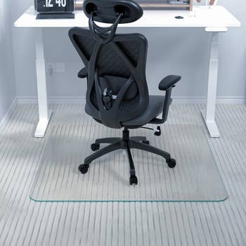 a desk set up with a black chair and the clear met with carpet