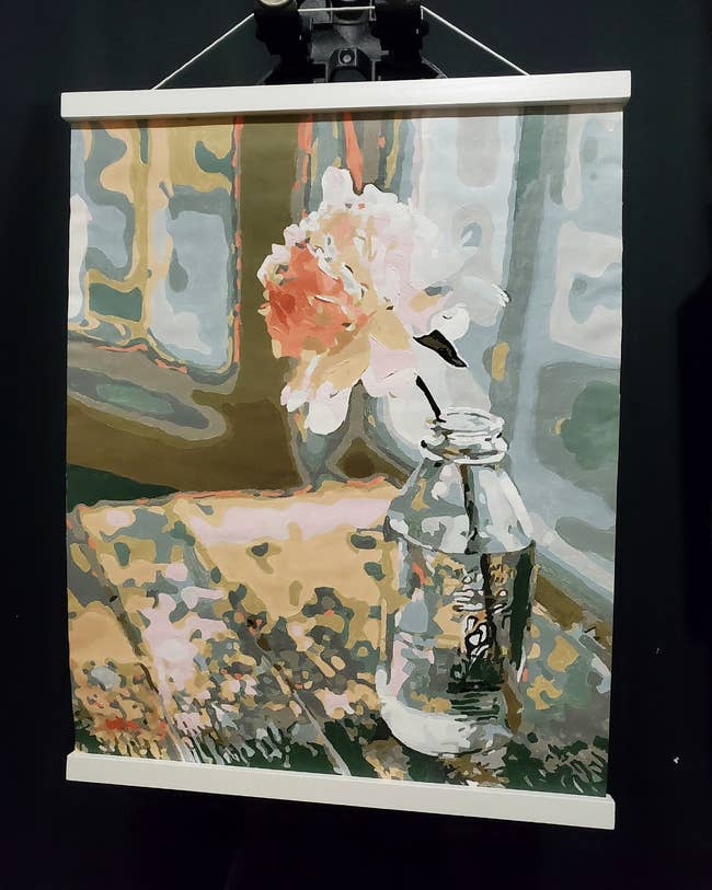 Reviewer's paint by number watercolor of a single pink flower in a vase on a rustic table 