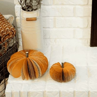 a model placing a large book pumpkin on a white fireplace