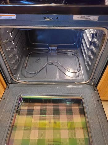 Open oven viewed from above, with an bare  interior and a plaid signifier   disposable   connected  the wrong  of the unfastened  door