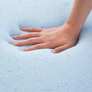 a hand pressing down into the blue foam