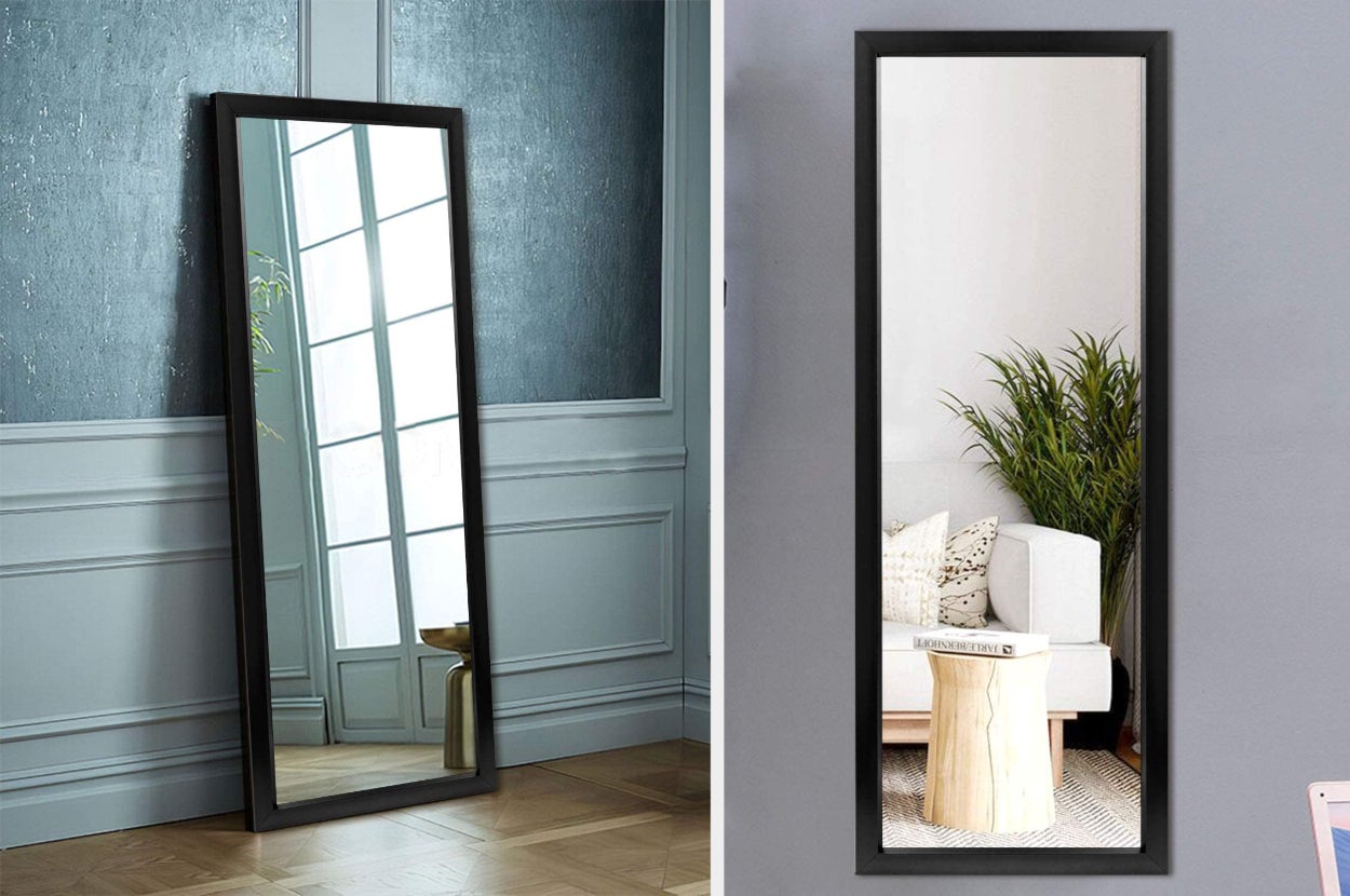 Black floor mirror against a blue and white wall, product hanging on a white wall showing reflection of white couch, floor plant, and small coffee table