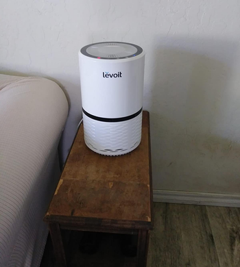 reviewer image of the white levoit air purifier on an accent table