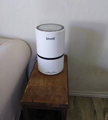 reviewer image of the white levoit air purifier on an accent table
