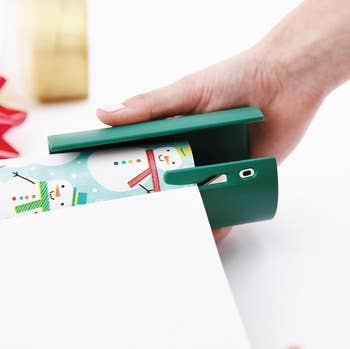 a rounded green tool used to slice wrapping paper