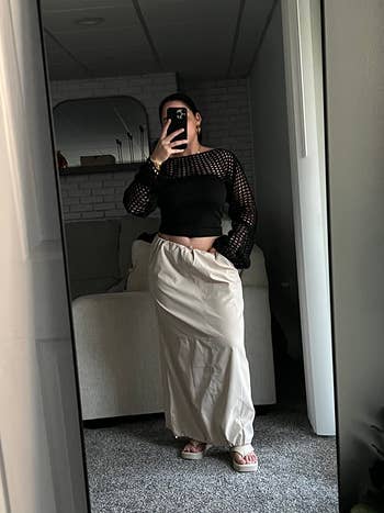reviewer in mirror selfie wearing a black mesh top and cargo skirt, paired with open-toe sandals