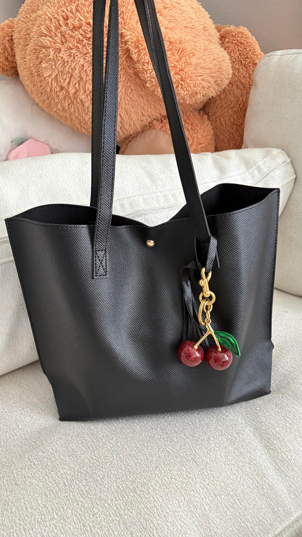 Black tote container  with cherry charm connected  sofa; ample  teddy carnivore  and cushion backdrop