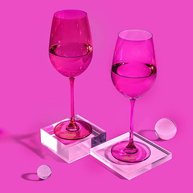 One hot pink and one light pink stemmed translucent wine glass with a small Barbie label on the base 