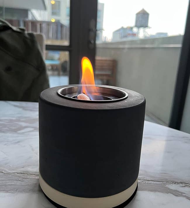 reviewer's small black tabletop fireplace with a lit flame in the center