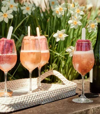 light pink wine glasses with boozy popsicle drinks inside of them on table