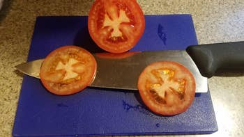 reviewer photo of the knife next to cut tomatoes showing the tomatoes are cut cleanly and not smushed