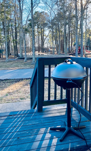 a reviewer photo of the grill with silver lid on a backyard deck