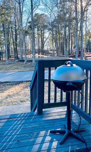 a reviewer photo of the grill with silver lid on a backyard deck
