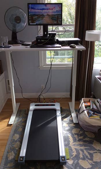 the white treadmill under a reviewer's standing desk setup