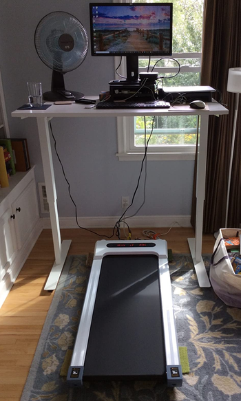 the white treadmill under a reviewer's standing desk setup