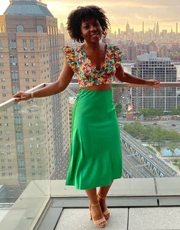 reviewer wearing the green skirt with a colorful crop top and tan heeled sandals