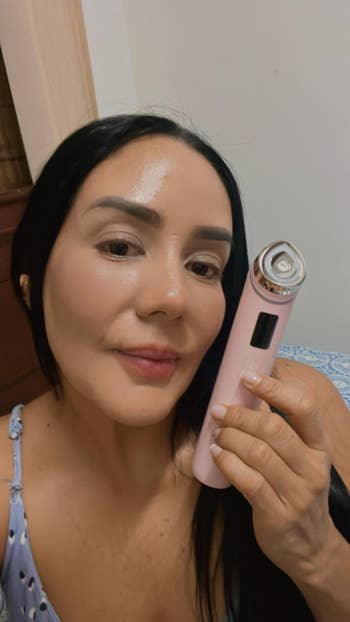 Person smiling and holding a handheld beauty device close to their face