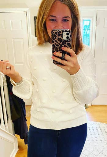 reviewer wearing the white pom pom sweater with jeans