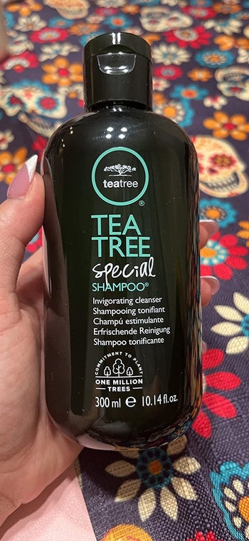 reviewer holding bottle of tea tree shampoo