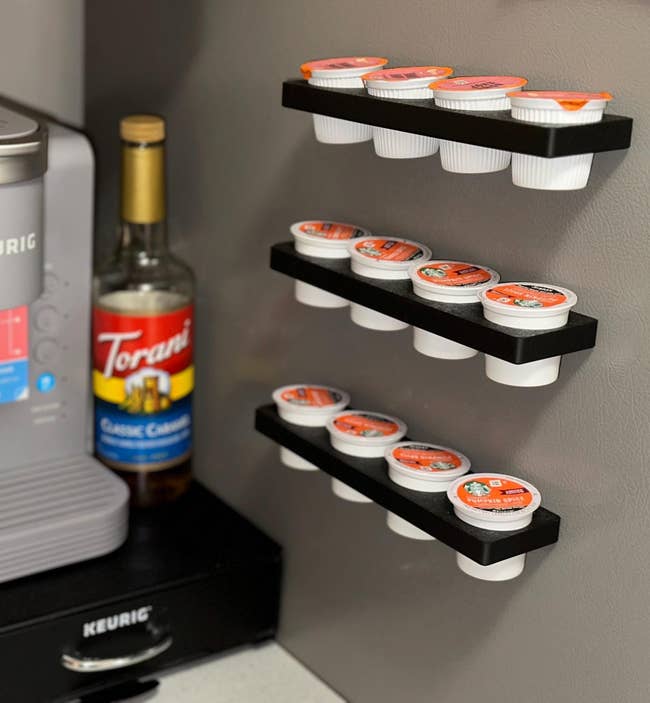 Coffee presumption with K-Cup pods connected wall-mounted racks, a Keurig instrumentality connected the left, and a vessel of java syrup beside it