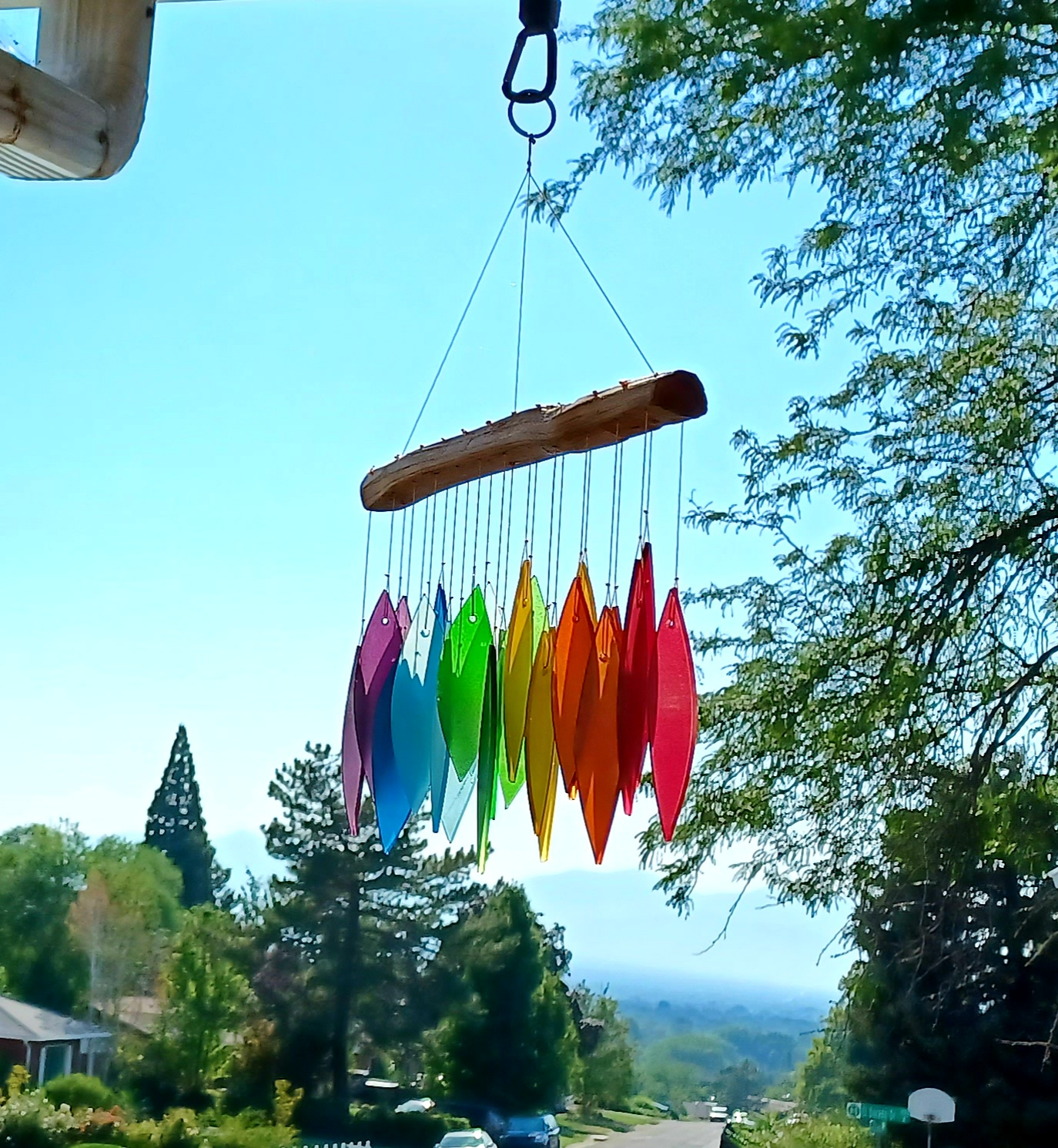 Multicolored upwind   chimes hanging outdoors with a scenic backdrop