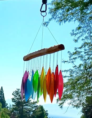 Multicolored upwind chimes hanging outdoors with a scenic backdrop