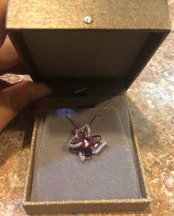 Reviewer image of the purple butterfly necklace in its box