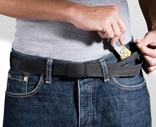 Person demonstrating an anti-theft money belt by placing cash into a hidden pocket. Caption below reads:
