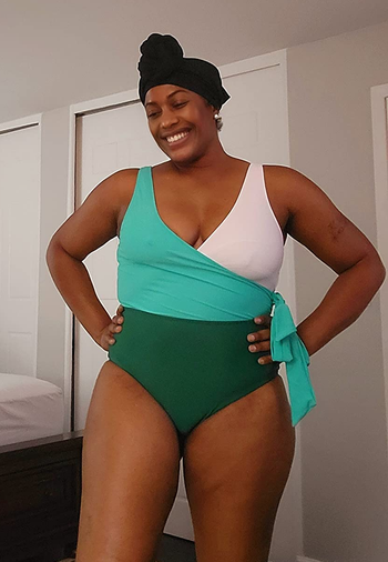 a reviewer wearing the one-piece bathing suit in green, teal, and white 