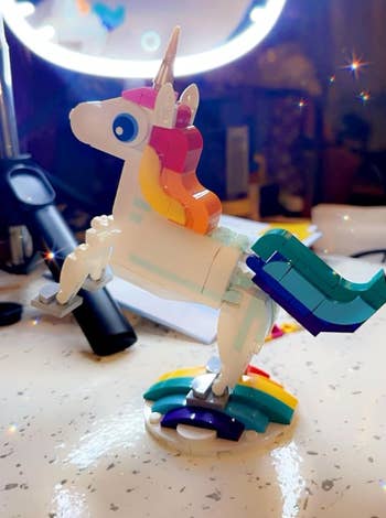 A LEGO unicorn figurine stands on a rainbow base 