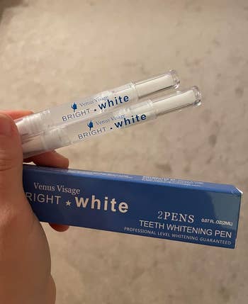 a hand holding the two teeth whitening pens