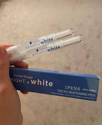 a hand holding the two teeth whitening pens
