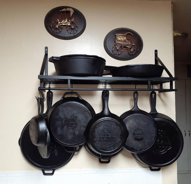 Reviewer image of wall mounted shelf with hooks and cast iron pots hanging 
