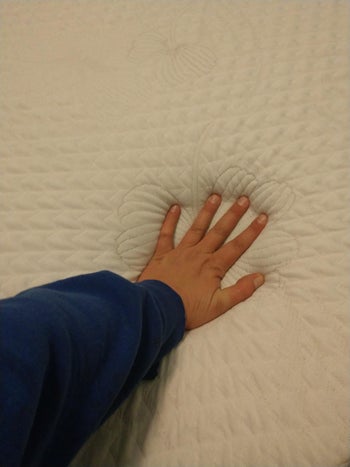 reviewer photo of their hand pressing into the mattress
