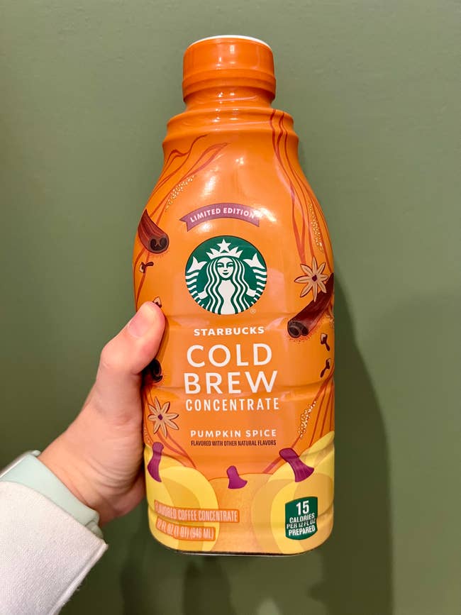Hand holding a vessel  of Starbucks Pumpkin Spice Cold Brew Concentrate, marked arsenic  constricted  edition, with 15 calories per 12 oz serving