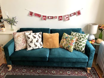 reviewer photo of the couch in green, adorned with throw pillows