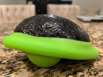 Avocado saver device with a half avocado inside on a kitchen counter
