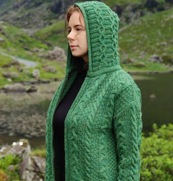 A model wearing a green hooded cardigan with a zipper
