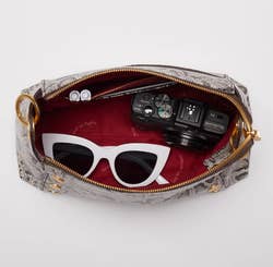 inside of the handbag with sunglasses, a camera, and pens inside 