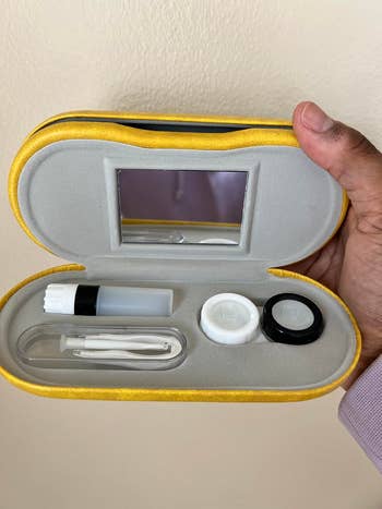 Contact lens lawsuit  acceptable   successful  an unfastened  yellowish  lawsuit  with compartments for solution, tweezers, holders, and mirror. Held by a hand