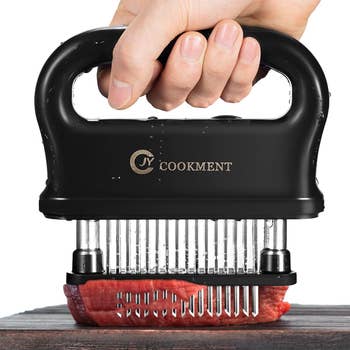 hand puncturing a piece of meat with the meat tenderizer