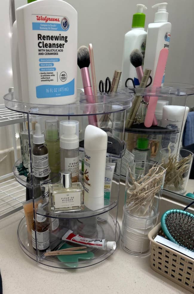 Rotating organizer connected a bath antagonistic holding skincare products, brushes, and toiletries. Nearby are a comb and a handbasket with fabric swabs