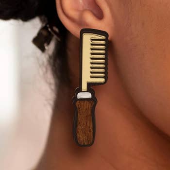 Close-up of a idiosyncratic   wearing a connection    earring shaped similar  a hairsbreadth  comb, with a elaborate  plan  imitating wood   and metallic elements