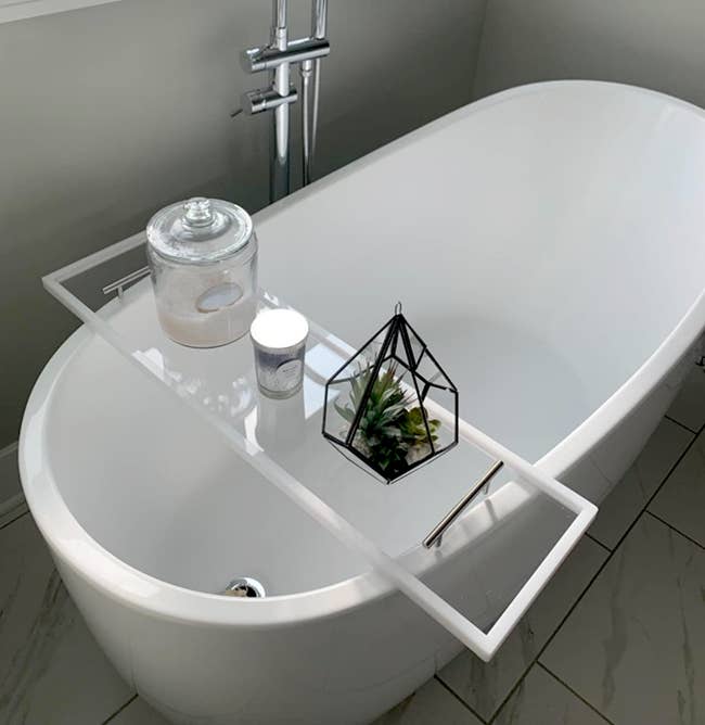 clear tray added over bathtub and styled with a plant, candle, and bath salts